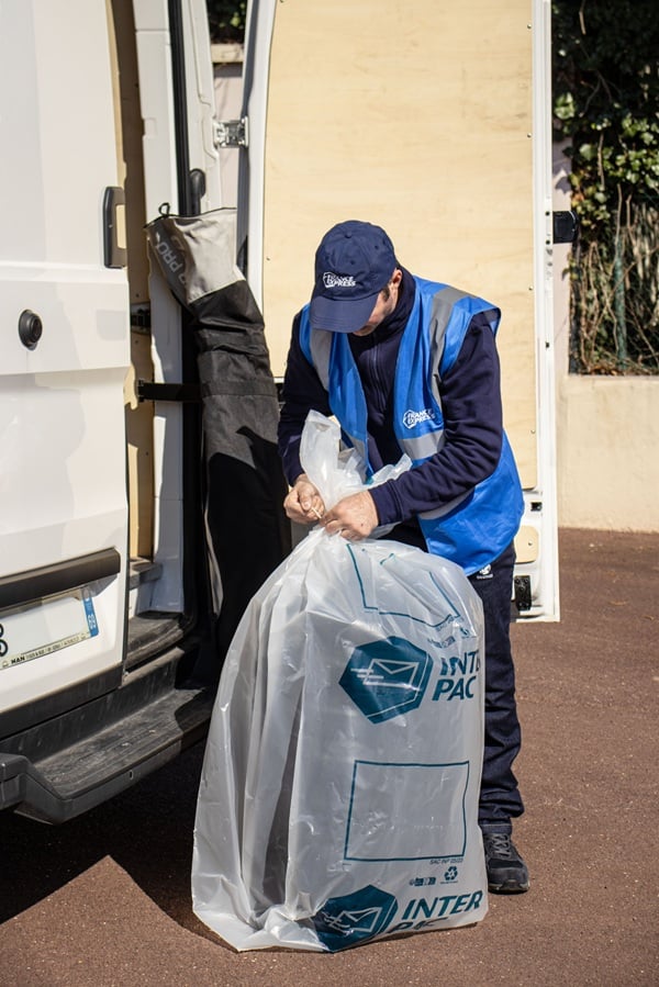 Un livreur charge un sac de bagages dans son véhicule
