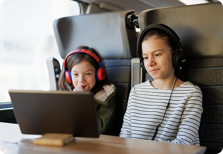Deux enfants portant des écouteurs regardant du contenu sur une tablette à bord du train
