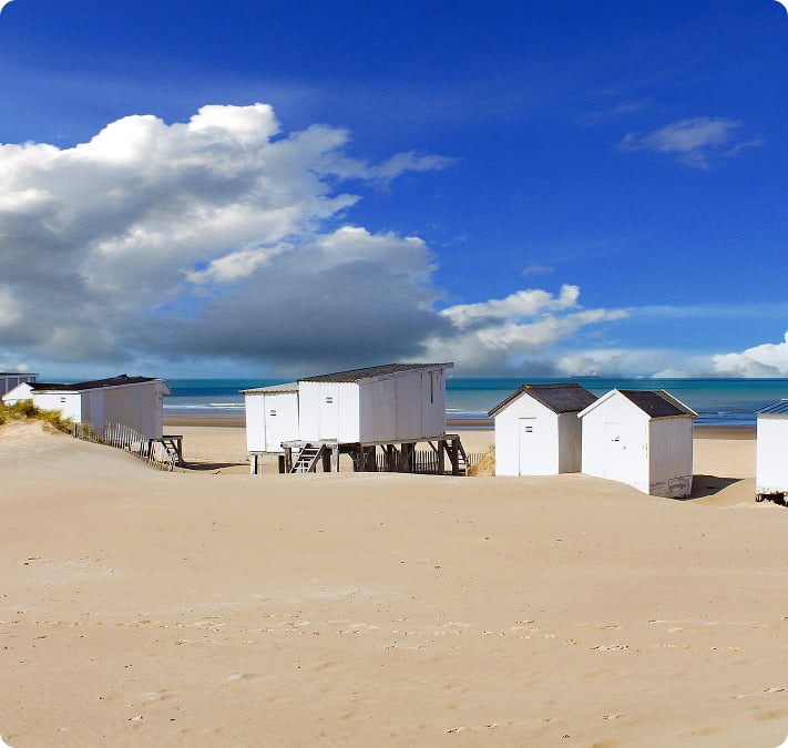 Des cabines de plage blanches alignées devant les dunes