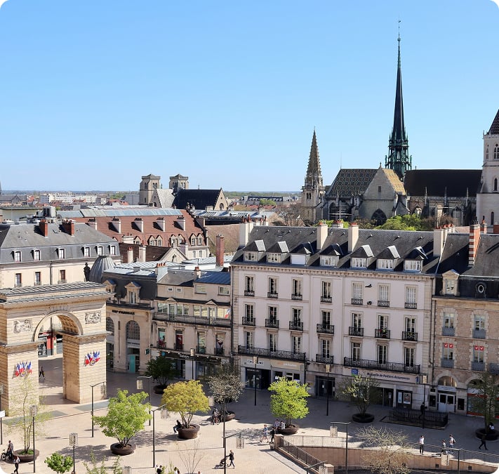 Vue en hauteur sur une place de Dijon, ses façades classiques et la flèche de la cathédrale
