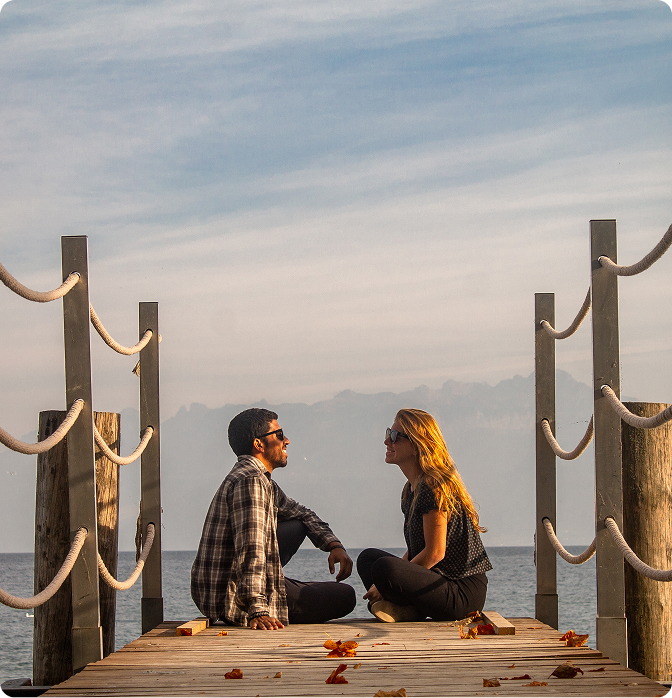 Un couple assis sur un ponton au bord du Lac Léman au coucher du soleil