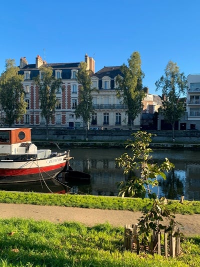 Un bateau amarré sur le canal, bordé d’arbres et de maisons en pierre