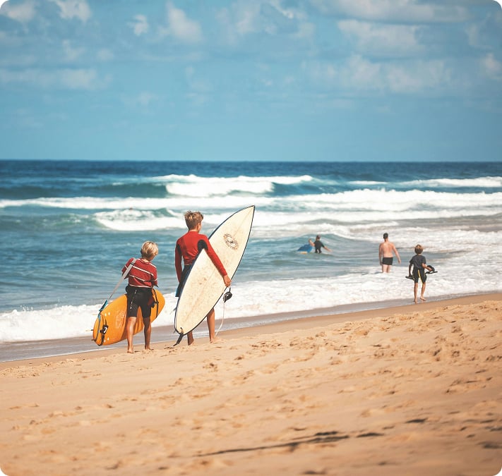 Deux surfeurs marchant sur la plage, leur planche sous le bras