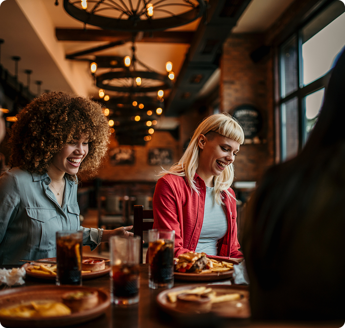 Deux amies souriantes attablées dans un restaurant